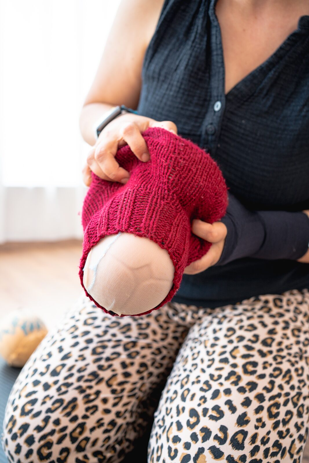 Gestricktes Uterusmodell wird über den Kopf einer Übungspuppe gezogen
