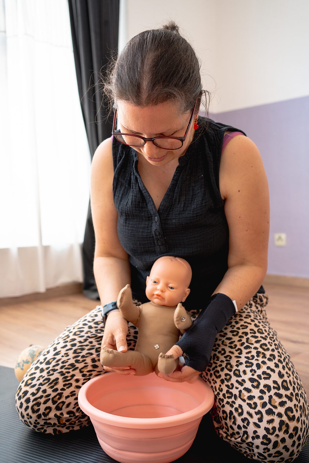 Hebamme hält eine Übungspuppe über einer Schüssel ab