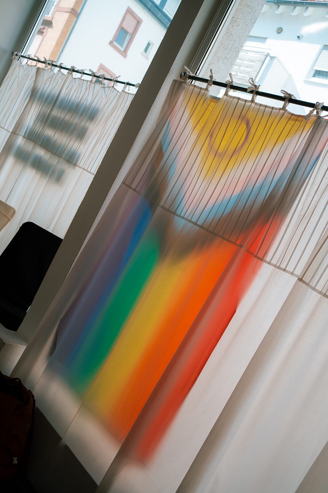 Vorhang mit gedrucktem Regenbogen- und Sonnenmotiv am Fenster