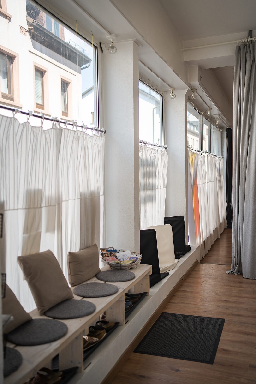 Lange Fensterfront mit hellen Vorhängen über der Sitzbank