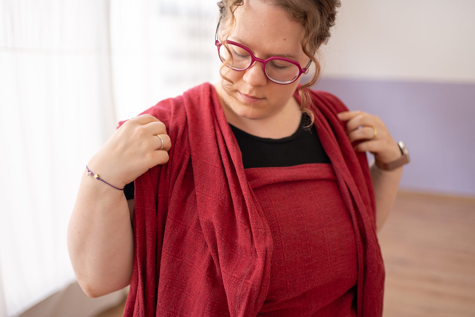 Hebamme legt sich ein rotes Tragetuch um die Schulter