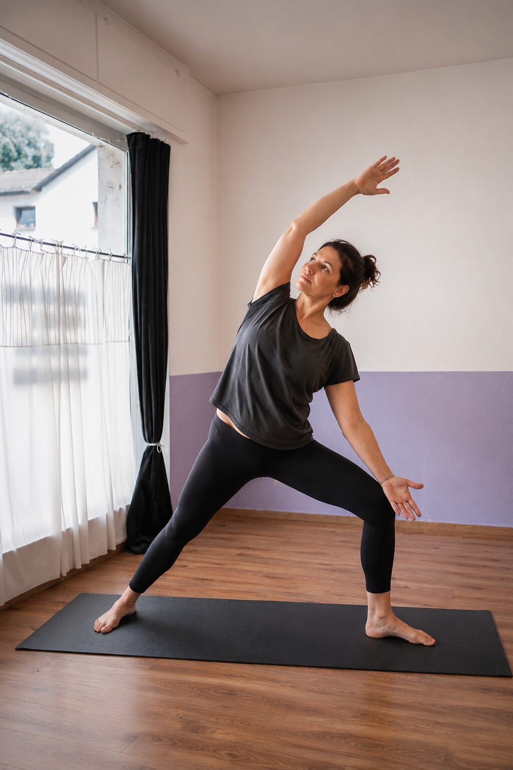 Frau im umgekehrten Krieger, einer Yogahaltung mit seitlicher Dehnung, im Kursraum der Praxis