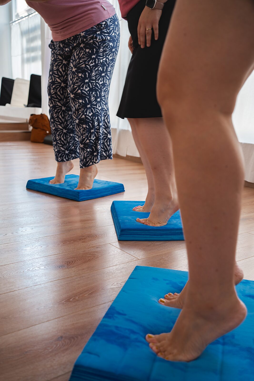 Schwangere im Stand auf einer Yogamatte, barfuß auf Balancekissen
